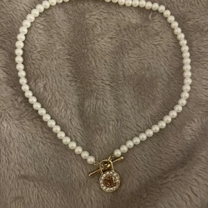 Pärlhalsband från Ralph Lauren - Elegant pärlhalsband från Ralph Lauren med vita pärlor och ett guldfärgat lås. Använt 4 gånger 