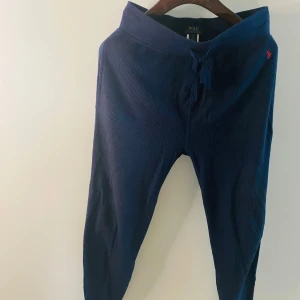  Polo Ralph Lauren mysbyxor - Mörkblå mjuka byxor från Polo Ralph Lauren med snörning i midjan. Byxorna har en ribbad textur och en liten broderad logga på sidan. 