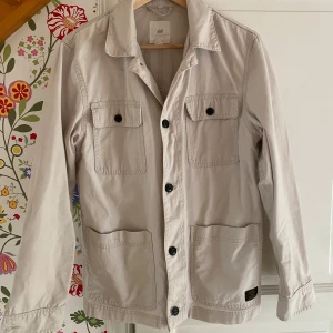 Overshirt från H&M - Säljer en snygg beige overshirt från H&M i storlek S, passar jättebra i M även. Perfekt för vår och höst, och funkar både till vardags och lite mer uppklädda tillfällen. Materialet känns slitstarkt och bekvämt. Den är i väldigt bra skick men är lite smutsig, det går väldigt lätt bort i tvätten. Passa på att fynda denna stilrena jacka! 