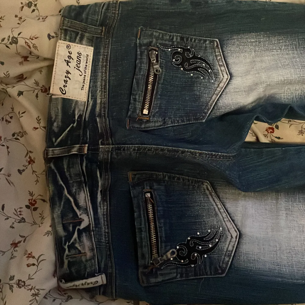 Snygga blå jeans från Crazy Age med coola broderade detaljer på framsidan och bakfickorna. De har en klassisk femficksdesign och dragkedjor på bakfickorna för extra stil. dm för flera bilder eller frågor! st38 men passar 36. Jeans & Byxor.