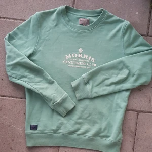 Ljusgrön Morris tröja - Säljer en snygg ljusgrön sweatshirt från Morris med tryck på bröstet. Tröjan är i bra skick och perfekt för både höst och vinter. Priset är inte i hugget, skriv ifall du är intresserad eller har några frågor!