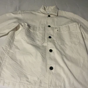 Vit jacka från Calvin Klein - Säljer en stilren vit jacka från Calvin Klein i storlek XS fast den kan även passa en person som har storlek S. Jackan är i toppskick där den bara använts 1-5 gånger. Jackan har en klassisk design med svarta knappar och två stora fickor framtill. Perfekt för vår och sommar! 🖤Ordinare pris 1300kr