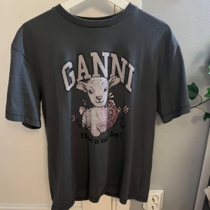 Grå Ganni t-shirt   - Säljer en superfin grå t-shirt från Ganni i storlek XXS. Den har ett gulligt fårmotiv och texten 'Have a nice day!'. Perfekt för en avslappnad stil. T-shirten är i bra skick och gjord av mjukt material. Passar perfekt till jeans eller shorts! Passar även S/M😇Använd 1 gång! Den är som ny😍