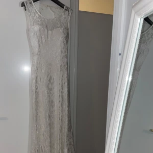 Vit spetsklänning - Elegant vit långklänning i spets med vackra detaljer. Klänningen har en öppen rygg och är ärmlös, perfekt för sommarens fester eller bröllop. Den har en figurnära passform som framhäver silhuetten. Ett måste för den stilmedvetna!