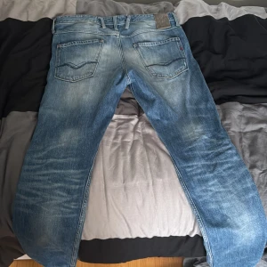 Blå jeans från replay - Säljer ett par snygga blå jeans från replay i bra skick. De har en klassisk femficksdesign och en lätt slitning för en cool look. Perfekta för både vardag och fest! Passar bra med en t-shirt eller skjorta.