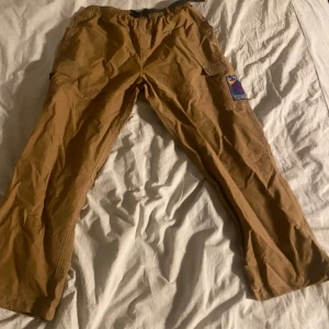 Bruna cargobyxor från Butter Goods - Säljer ett par bruna cargobyxor i nyskick från butter goods använda 1-2 gånger. Perfekta för en avslappnad stil eller utomhusaktiviteter. Byxorna har en normal passform och är gjorda i ett slitstarkt material. Köpta för 1200 på junkyard