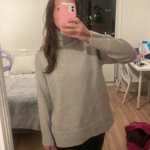 Beige stickad polotröja - Mysig beige stickad polotröja i oversized passform. Perfekt för kalla höst- och vinterdagar. Tröjan har långa ärmar och ribbade detaljer vid ärmslut och nederkant. Superbekväm och stilren!