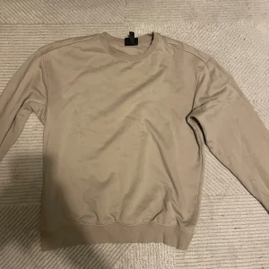 Beige tröja från H&M - Säljer en stilren beige tröja från H&M i storlek XS. Perfekt för en avslappnad look, med normal passform och långa ärmar. Materialet känns mjukt och bekvämt, idealiskt för både vår och höst. Passar bra till jeans eller chinos för en casual stil.