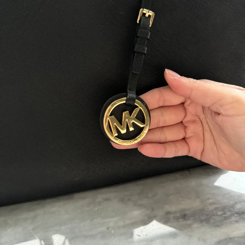 Säljer en elegant svart handväska från Michael Kors i mycket bra skick. Väskan har en stilren design med guldiga detaljer och ett klassiskt MK-hänge. Perfekt för både vardag och fest! 🖤 det finns små repor på hänget, kolla bild nr 3. Inget som man tänker på eller lägger märke till och syns inte tydligt från långt avstånd. Själv får jag plast med mitt cykelbatteri och skoldator i den. Nypris: Ca 3000kr. . Laukut & Käsilaukut.