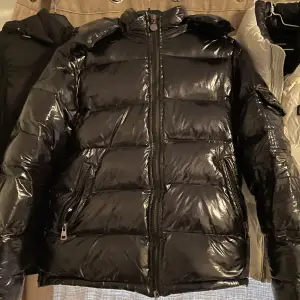 Säljer en snygg svart pufferjacka från Moncler i mycket bra skick. Jackan är perfekt för vintern med sitt blanka polyester-material och har en dragkedja framtill. Den är långärmad och har en cool Moncler-logga på ärmen. Perfekt för att hålla sig varm och stilren under kalla dagar! 🖤