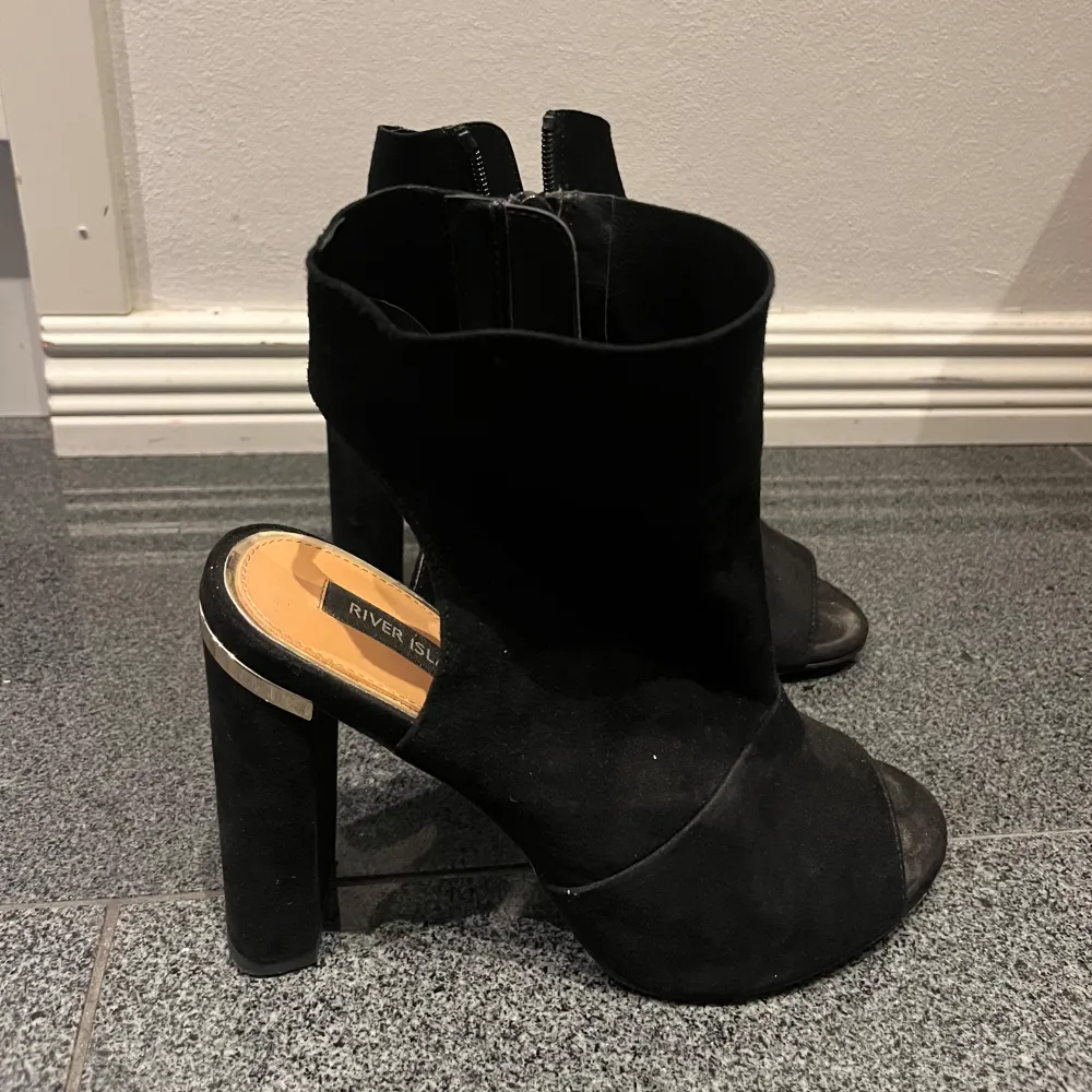 Snygga svarta boots från River Island i mocka med öppen tå och dragkedja på sidan. De har en stabil klack som ger lite extra höjd och stil. Perfekta för både fest och vardag! 🖤. Skor.