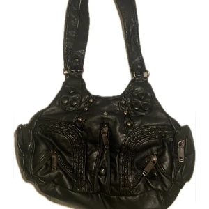 Svart axelväska  - Snygg svart axelväska i skinn med flera dragkedjor och nitar som detaljer! jätte bra skick och inga defekter 💕💕 skriv vid frågor! 24x33 cm