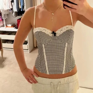 Svartvit rutig korsett - Säljer en superfin svartvit rutig korsett med spetsdetaljer och en söt liten rosett framtill. Den har smala axelband och en tight passform. Formar kroppen perfekt🩷Perfekt festopp !! Säljer direkt för 550kr