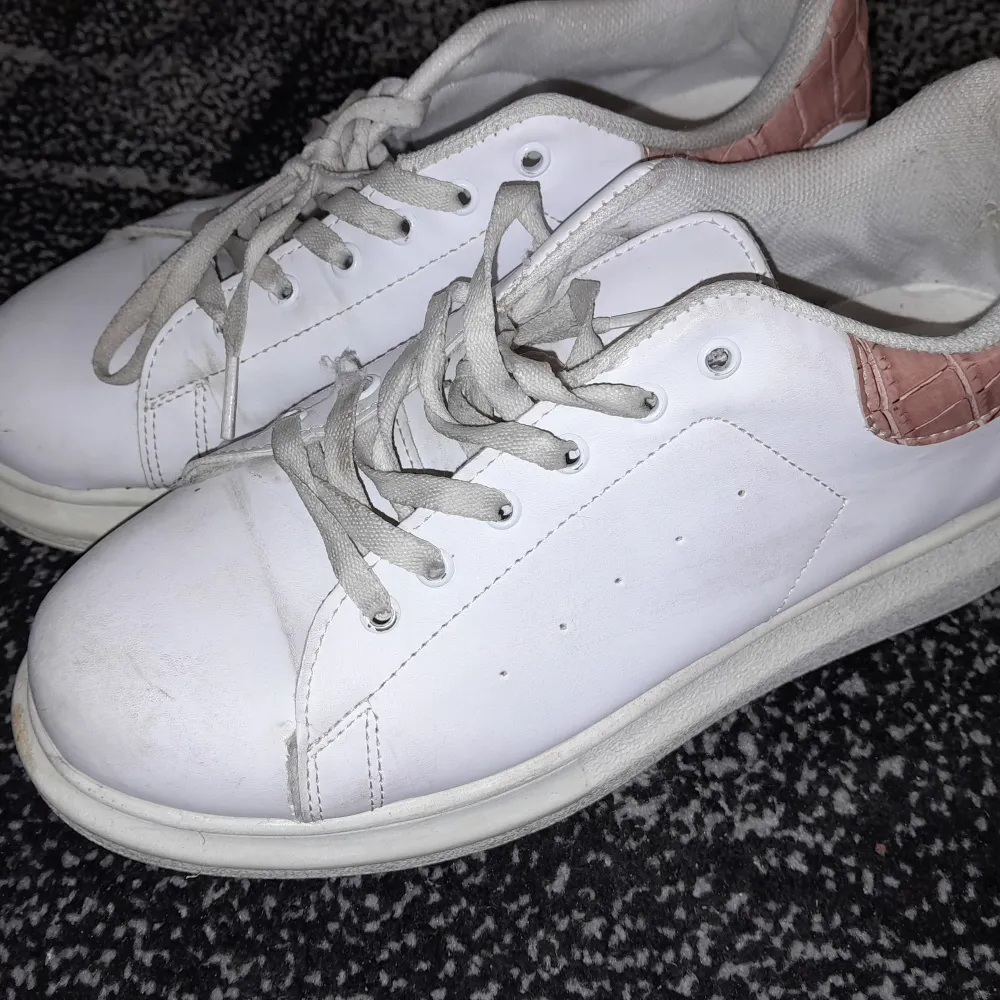 Säljer ett par vita sneakers från M Shoes i bra skick. De har snygga rosa detaljer på hälen och klassisk snörning. Perfekta för vardagsbruk och ger en stilren look. Sulan har ett unikt mönster som ger bra grepp.. Skor.