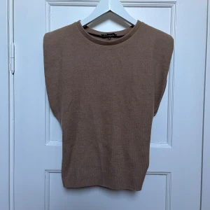 Beige ärmlös topp - Säljer en stilren beige ärmlös topp i mjukt material. Perfekt för lager-på-lager eller som den är under varmare dagar. Enkel och tidlös design som passar till det mesta. Ett måste i garderoben för en minimalistisk look.