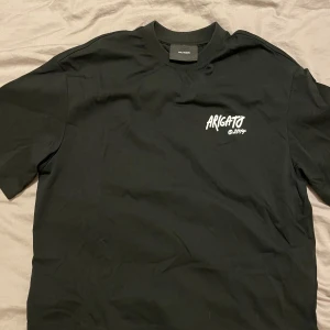 Svart t-shirt från Axel Arigato - Säljer en svart t-shirt från Axel Arigato i mycket bra skick. Den har en cool vit text 'Arigato' tryckt på bröstet. Perfekt för en avslappnad stil och passar till nästan allt. T-shirten är gjord i mjuk bomull och har en normal passform. Perfekt för både vardag och fest! Passar både killar och tjejer, priser går alltid att diskutera🤩
