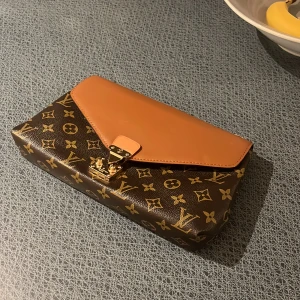 Louis Vuitton pallas chain shoulder bag - Säljer en snygg väska från Louis Vuitton i brunt och beige med klassiskt monogrammönster. Väskan är i bra skick och sporadisk använd!