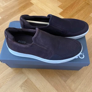 Bruna sneakers - Säljer ett par snygga bruna skor från Ecco i mycket bra skick. De är gjorda i skinn och har en vit sula som ger en fräsch kontrast. Perfekta för både vardag och lite finare tillfällen. Skorna är bekväma och lätta att ta på och av. Passar perfekt till höst och vår!