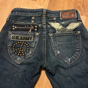 Jeans med U.S. Army detaljer - Jeans från Robin’s jeans som är omsydda, storlek 25 på lappen (jeansen är inte i det bästa skicket, och kan behöva fixas vilket är varför de är ett lågt pris)