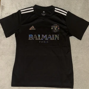 Adidas Balmain x Manchester United tröja - Säljer en helt oanvänd svart adidas Balmain x Manchester United tröja. Perfekt för fans som vill ha något unikt och stilrent. Passar både till match och vardag🤩⚽️🏟️