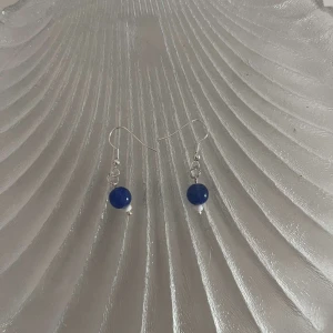 Blå pärlörhängen - Snygga och enkla örhängen med blå pärlor. Perfekta för att ge en färgklick till din outfit. De har en silverfärgad krok och är lätta att bära hela dagen. Passar både till vardag och fest!