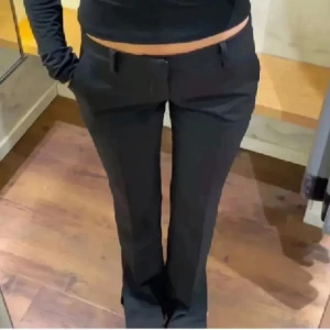 Svarta kostymbyxor - Snygga svarta kostymbyxor i lågmidjad modell. De har en klassisk och stilren design med flared ben och diskreta fickor. Perfekta för både kontoret och festligare tillfällen. Passar bra till en chic topp eller en elegant blus.