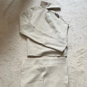 Beige stickad set med polotröja - Säljer ett snyggt och bekvämt beige stickat set med en polotröja och matchande kjol. Perfekt för höst och vinter! Tröjan har en stilren design med långa ärmar och en hög krage. Kjolen är i samma mjuka material och har en smickrande passform. Perfekt för både vardag och fest! 🧶✨