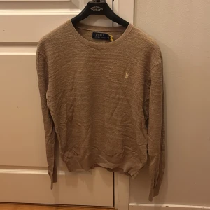 Beige tröja från Polo Ralph Lauren - Säljer en stilren beige tröja från Polo Ralph Lauren i storlek S. Tröjan är i perfekt skick då den används max 4 gånger och har en klassisk design med rund hals och långa ärmar. Perfekt för all användning, och den är gjord i ett mjukt material som känns skönt mot huden. Priset kan förhandlas. 