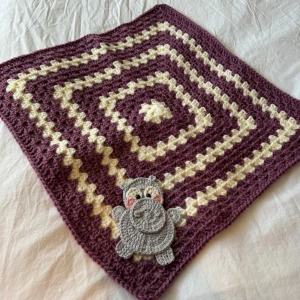 Handgjord virkad filt med flodhästmotiv - En superfin handgjord virkad filt i lila och beige med ett gulligt flodhästmotiv i hörnet. Perfekt som en mysig detalj i barnrummet eller som en present till en nyfödd. Filten är kvadratisk och har ett härligt mönster som ger en hemtrevlig känsla. 🦛💜virkad i Akrylgarn