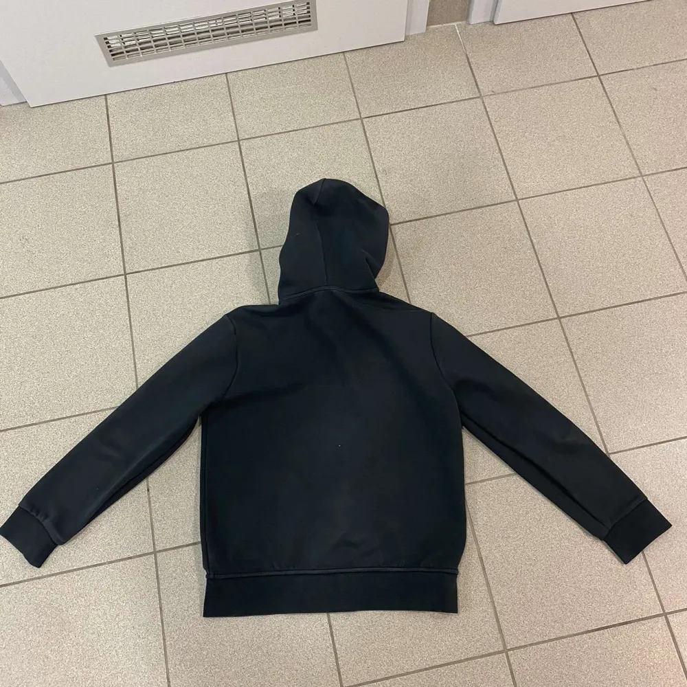 Säljer en stilren svart hoodie från Ralph Lauren i mycket bra skick. Den har en dragkedja framtill och en klassisk logga på bröstet. Perfekt för höst och vinter, med en skön passform och praktiska fickor. Perfekt för både vardag och chill.. Tröjor & Koftor.