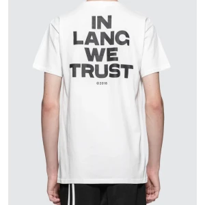 Vit t-shirt från Helmut Lang - Säljer en stilren vit t-shirt från Helmut Lang med texten 'IN LANG WE TRUST' på ryggen och 'HELMUT' på bröstet. T-shirten har en normal passform och är kortärmad, perfekt för en avslappnad look. Passar både till vardags och fest!