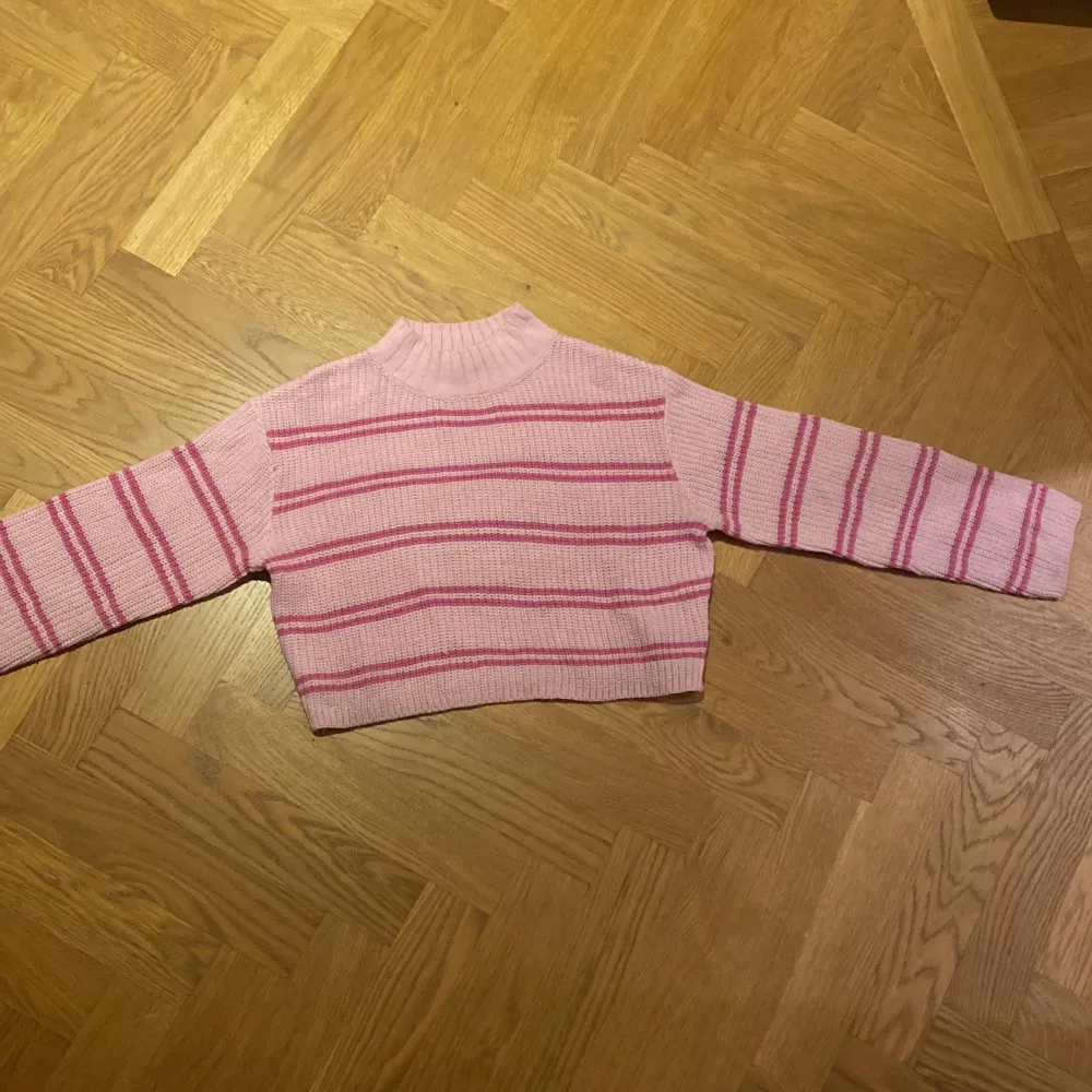 Säljer en superfin rosa stickad tröja från H&M med mörkrosa ränder. Den är croppad och har en mysig ribbad krage. Perfekt för höst och vår! Passar både till vardags och lite festligare tillfällen. 🩷. Tröjor & Koftor.