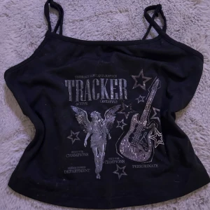 Svart linne med tryck - Coolt svart linne med ett rockigt tryck av en gitarr och stjärnor. Perfekt för en avslappnad och trendig look. Linnet har smala axelband och är i ett mjukt material som känns skönt mot huden.