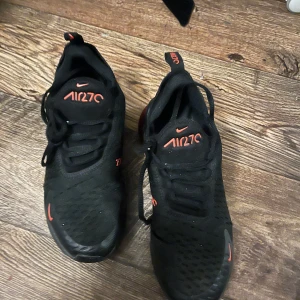 Svarta Nike Air Max 270 - Säljer ett par svarta Nike Air Max 270 i bra skick. De har en snygg design med röda detaljer och en bekväm passform. 