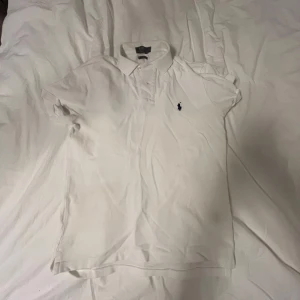 Vit pikétröja från Ralph Lauren - Säljer en klassisk vit pikétröja från Ralph Lauren i slim fit. Den har en broderad logga på bröstet och är i mycket bra skick. Perfekt för både vardag och festliga tillfällen. Passar bra till jeans eller chinos för en stilren look. Bra skick men behöver bara strykas👍