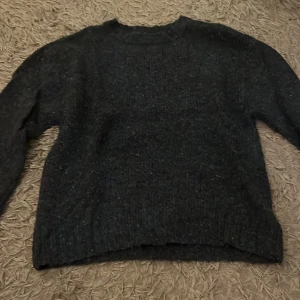 Mörkblå stickad tröja från Zara - Säljer en mysig mörkgrå stickad tröja från Zara. Perfekt för kyliga dagar med sin varma och bekväma passform. Tröjan har långa ärmar och en klassisk rund halsringning. Passar både till vardags och lite finare tillfällen.💙