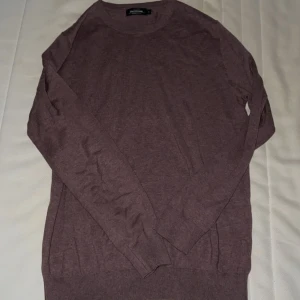 Brun tröja från Dressmann - Säljer en unik lilabrun långärmad tröja från Dressmann i Supima bomull. Perfekt för höst och vinter med sin mjuka och bekväma passform. Tröjan har ribbade muddar vid ärmslut och nederkant. Passar både till vardags och lite finare tillfällen.