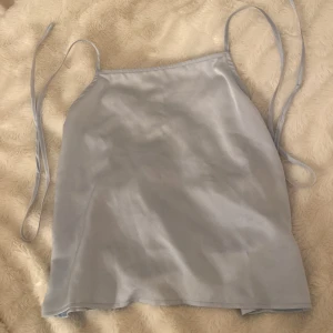 Satin linne  - Säljer detta jättefina ljusblåa satin linne i bra och fin skick, använd endast vid ett tillfälle och får ingen användning av den längre. Den sitter jättefint på när man knyter den där bak. Den är i storlek M. 