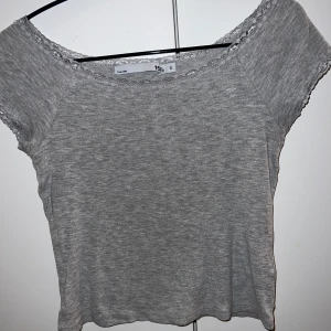Grå topp med spetsdetaljer - Säljer en söt grå topp från lager156 i storlek S. Den har korta ärmar och fina spetsdetaljer vid halsringningen och ärmsluten. Använd 1 gång