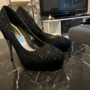 Snygga svarta glittriga pumps från Zanotti i storlek 38. Perfekta för festliga tillfällen med en elegant klack och spetsig tå. Skorna har en glamorös look med glittrande yta som verkligen sticker ut.