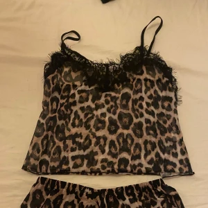 Leopardmönstrad pyjamas med spetsdetaljer - Säljer en snygg leopardmönstrad pyjamas med svarta spetsdetaljer. Toppen har tunna axelband och en lös passform. . Använt tröjan en gång men aldrig shortsen. Det är ett ganska genomskinligt tyg men tröjan blir knappt genomskinlig på❤️ man kan ha linnet som vanlig tröja också och inte bara pyjamas.