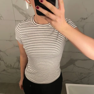 Randig t-shirt från Monki - Säljer en superfin randig t-shirt från Monki i storlek S. Den är vit med svarta ränder och har en tight passform. Perfekt för både vardag och fest! T-shirten är i mycket bra skick och gjord av mjukt material som känns skönt mot huden.