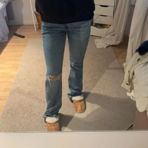 Blå jeans med slitningar - Säljer ett par snygga blå jeans i bra skick. De har en straight passform och är lite slitna vid knäna för en cool look. Perfekta för vardagsbruk och kan matchas med nästan vad som helst. Passar bra till både sneakers och boots.