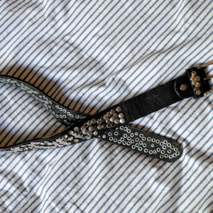 Svart nitat bälte - Säljer ett svart bälte i skinn med coola silvernitar. Köpt second hand, i bra skick. Ganska kort bälte 