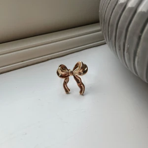 Guldfärgad ring med rosett - Superfin guldfärgad ring med en söt rosett på toppen. Perfekt för att ge en extra touch till din outfit. Den är elegant och passar både till vardags och festliga tillfällen. Justerbar och ny!