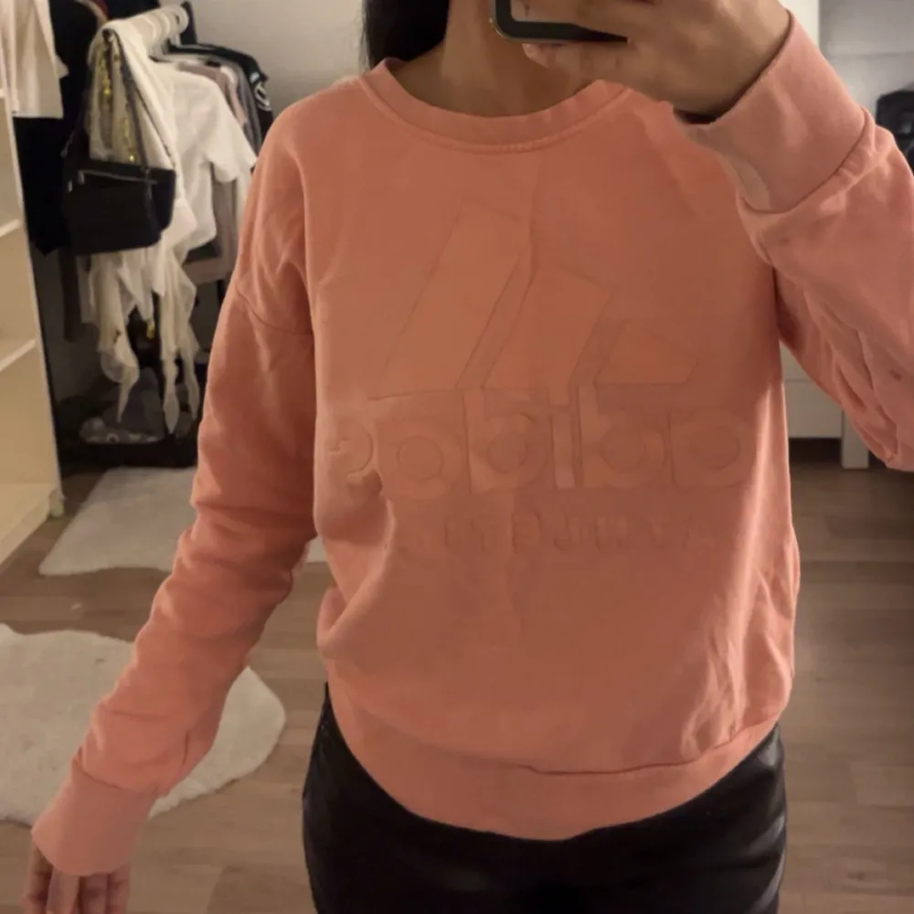 Säljer en superfin rosa sweatshirt från Adidas. Den har en diskret logga på framsidan och är perfekt för en avslappnad stil. Tröjan är långärmad och gjord i mjukt material, vilket gör den både bekväm och snygg. Passar perfekt till vardags eller chill dagar hemma. 💖. Tröjor & Koftor.