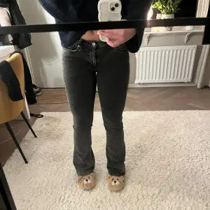 Säljer ett par snygga grå/svarta jeans i bootcut-stil. De är i bra skick och har en tight passform upptill som övergår i en lätt utsvängd nederdel. Perfekta för både vardag och fest!