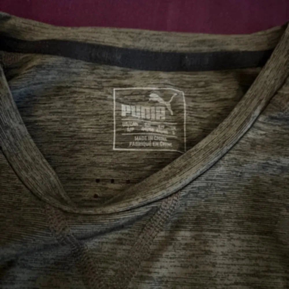 Säljer en grå tränings-t-shirt från Puma. Den är perfekt för träning med sitt lätta och bekväma material. T-shirten har ett diskret randigt mönster och Puma-loggan syns tydligt på bröstet. Den är i bra skick och redo för nya äventyr!. Sportswear.