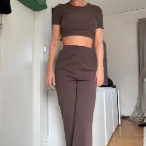 Säljer detta snygg bruna set med en croppad topp med korta ärmar och racka mjuka byxor. Perfekt för en avslappnad och stilren look. Toppen är tight medans byxorna sitter löst, du kan vika ner byxorna om du föredrar lågmidjat! 