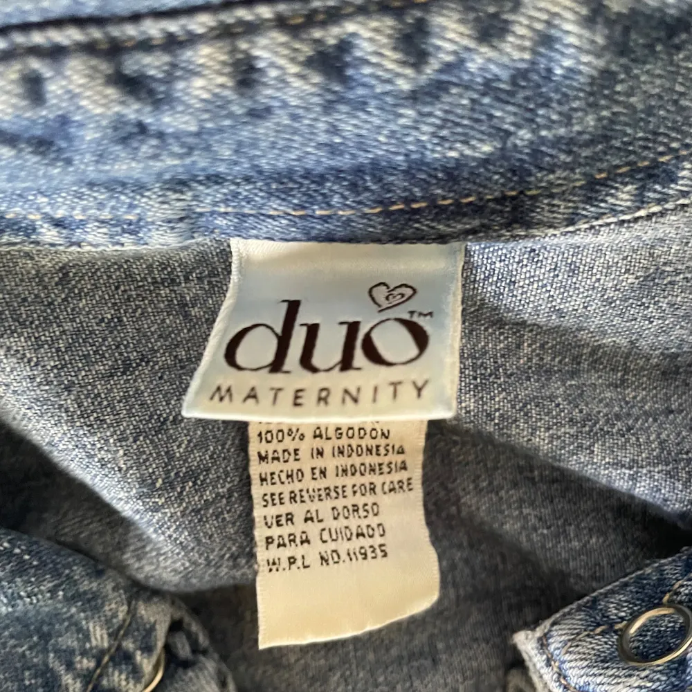 Säljer en snygg blå jeansskjorta från Duo Maternity. Skjortan är kortärmad och har knappar hela vägen fram. Den är tillverkad i 100% bomull vilket gör den både bekväm och hållbar. Perfekt för en avslappnad stil!. Paidat.